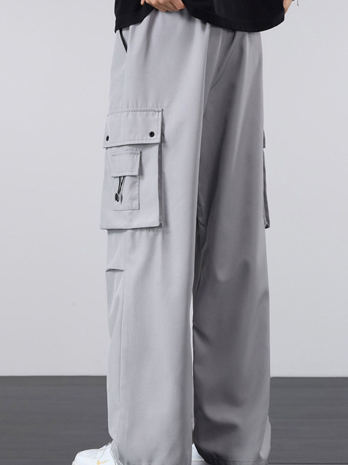 Light gray loose-fit cargo pants with drawstring waist and flap utility pocket