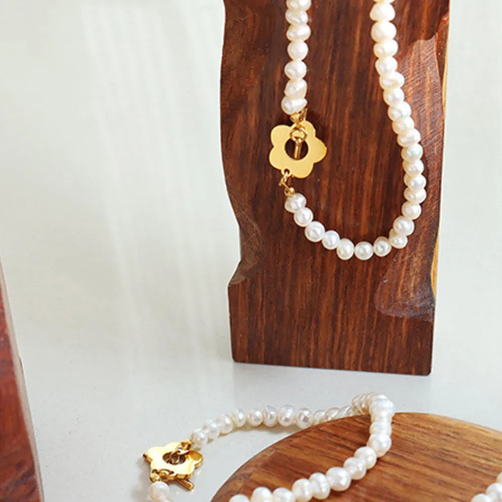 Pearl bead bracelet with gold flower clasp, shown as a strand