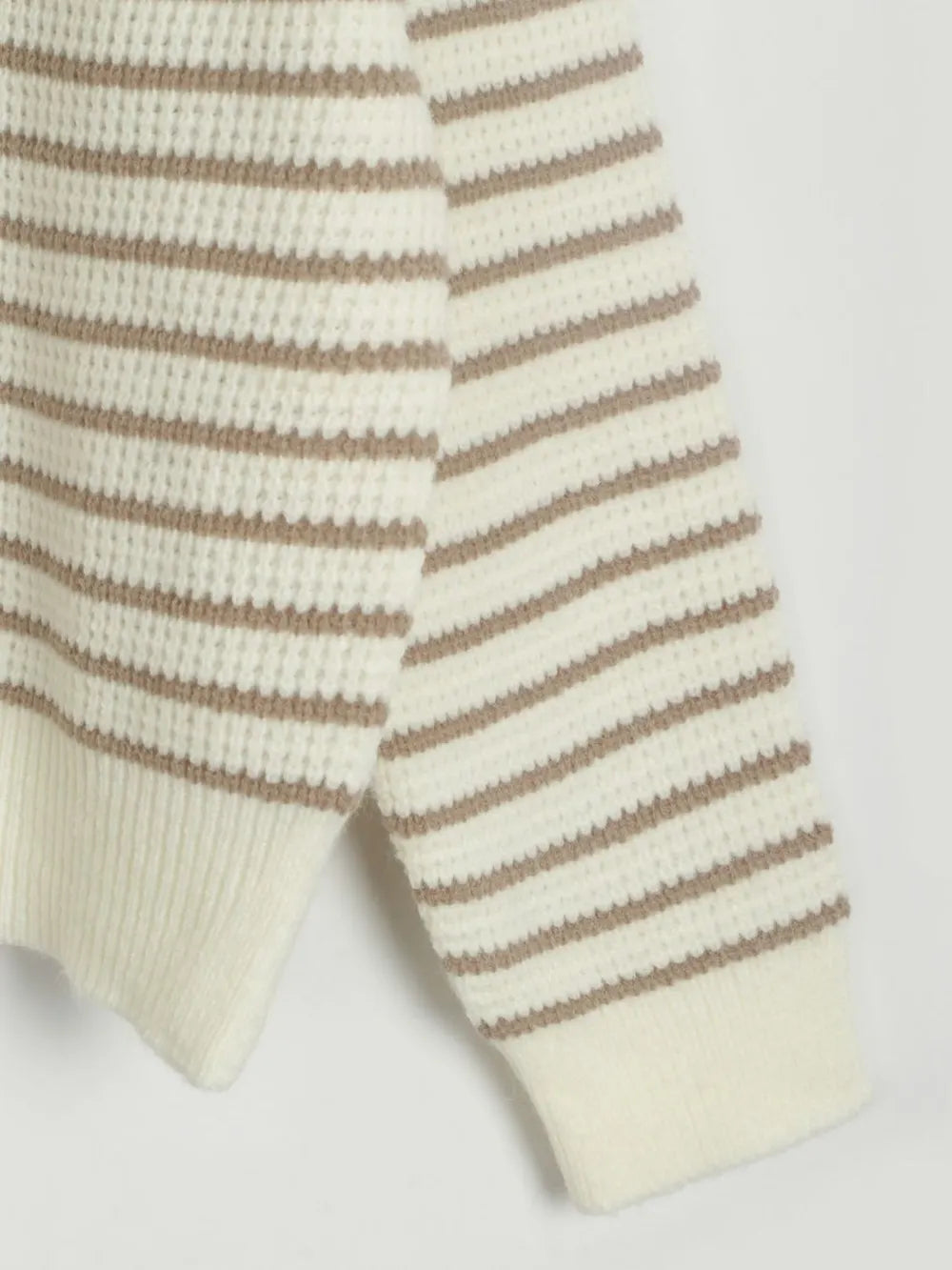 Cream knit sweater detail with caramel horizontal stripe bands and ribbed hem