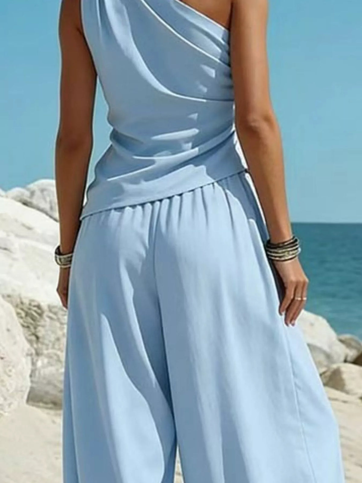 Light blue one-shoulder sleeveless top with draped detail and matching harem pants