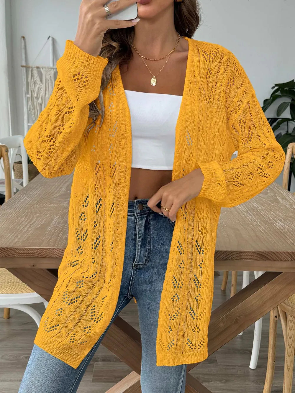 Gold openwork long-sleeve cardigan, open front, knit eyelet pattern and ribbed cuffs.