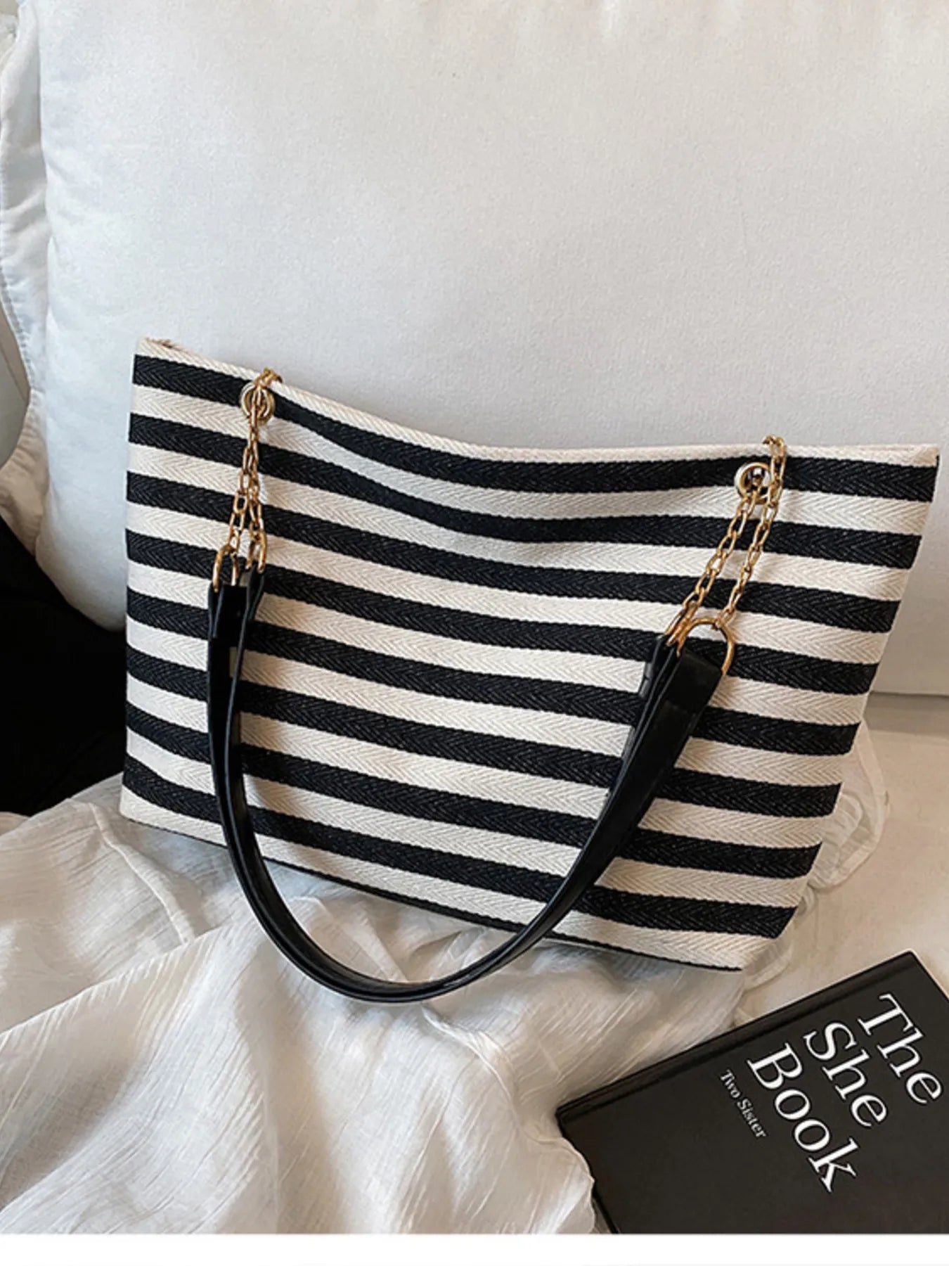 Black and white striped shoulder bag with gold chain handles and top zip closure.