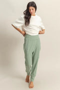 Sage green high-waist sweatpants with pocket detail and tapered cuffs