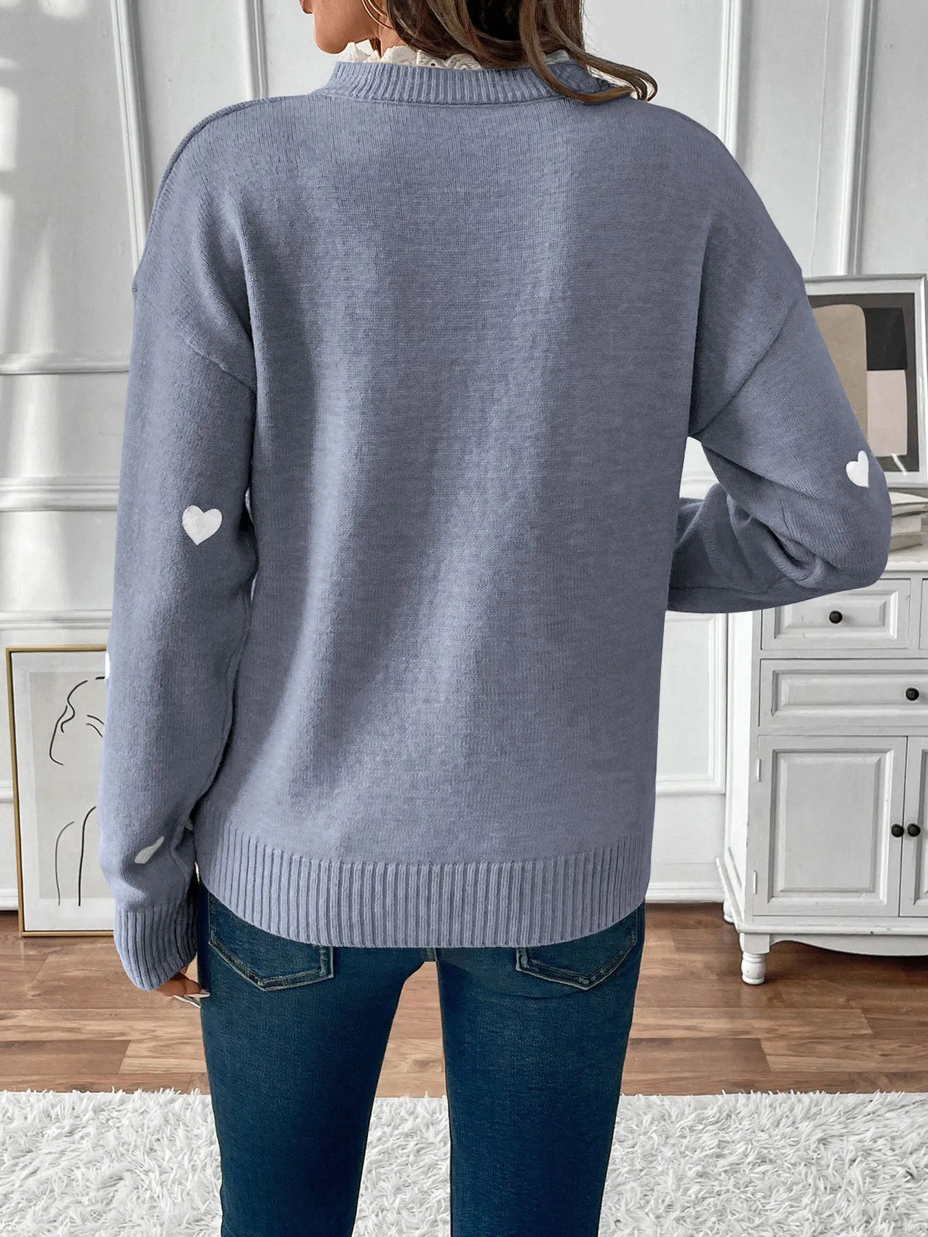 Blue long sleeve sweater back with small white heart motif and ribbed knit hem