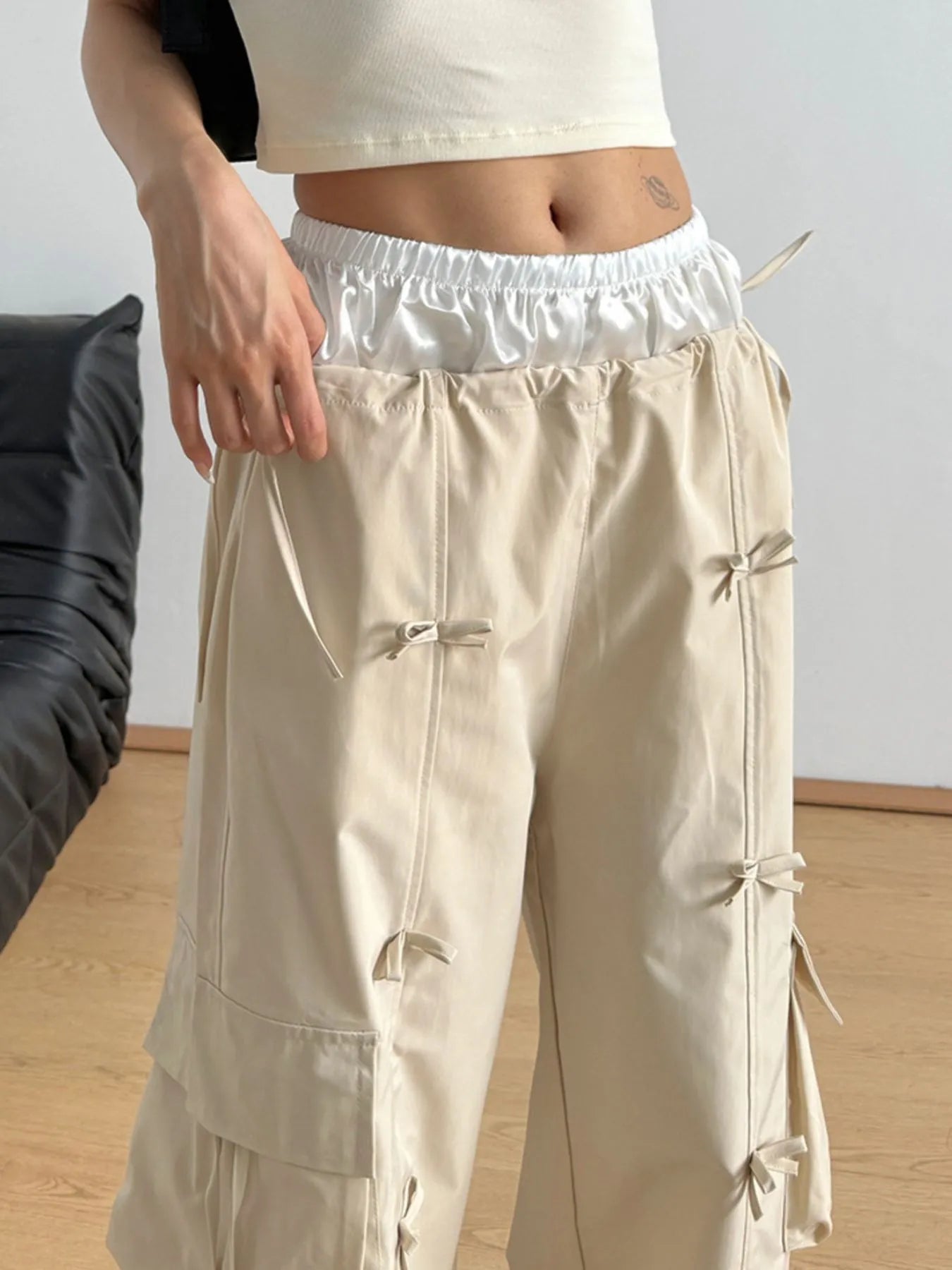 Tan cargo pants with elastic waistband and multi-pocket front with tie details