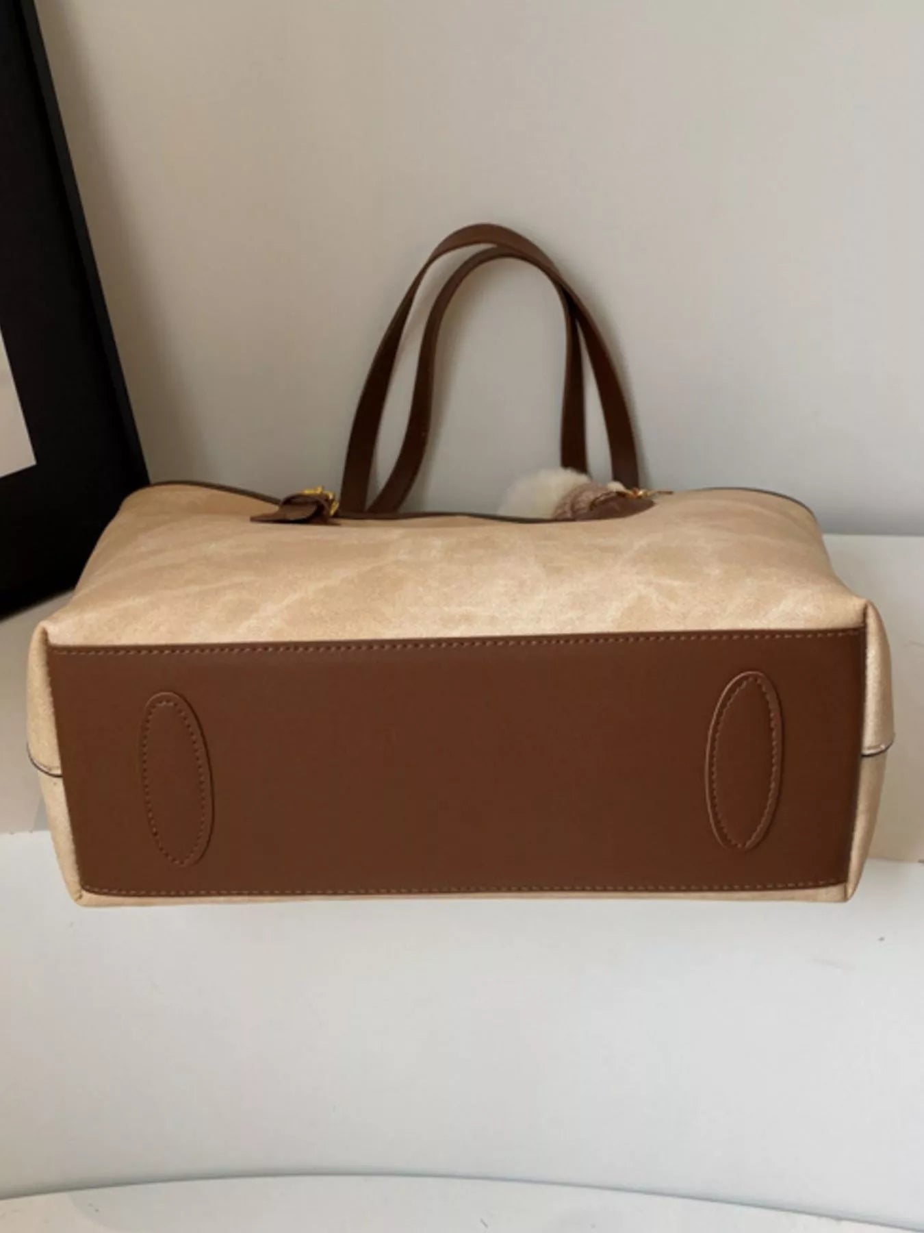 Shoulder bag with plush charm, beige PU body with brown leather bottom panel and dual brown handles