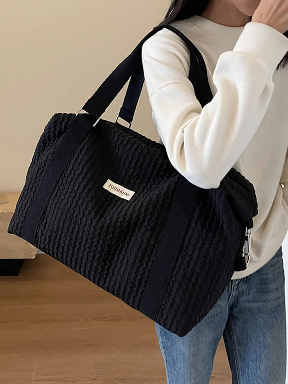 Black textured large duffle travel bag with top handles and shoulder strap