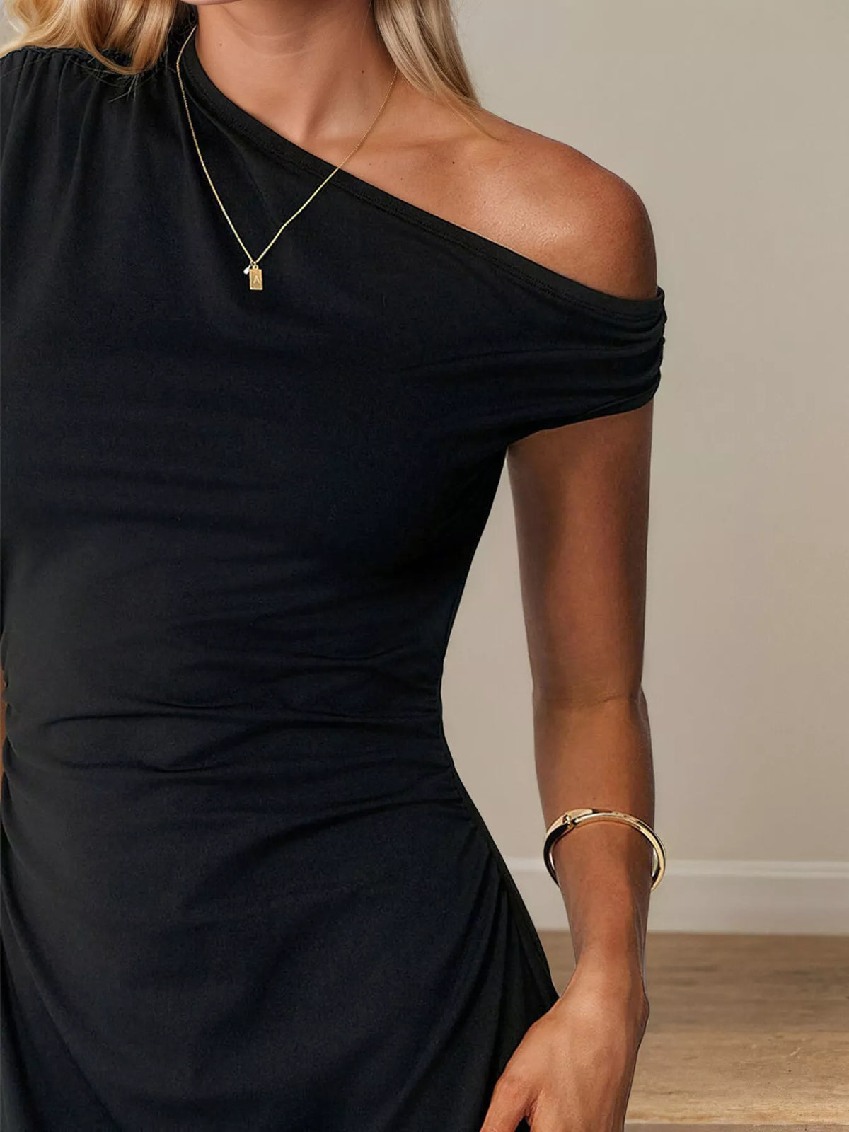 Black one-shoulder ruched mini dress close-up with asymmetrical neckline and side gather