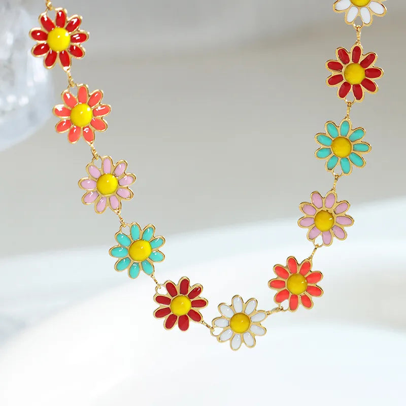 Gold link bracelet with multicolor enamel flower drops along the chain, close-up