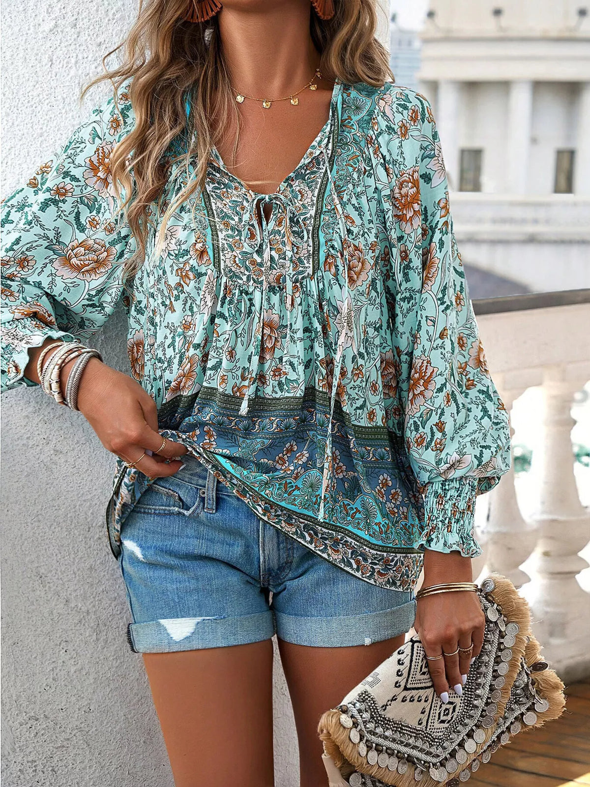 Teal floral tie-neck blouse with gathered yoke and long puff sleeves, smocked cuff accents