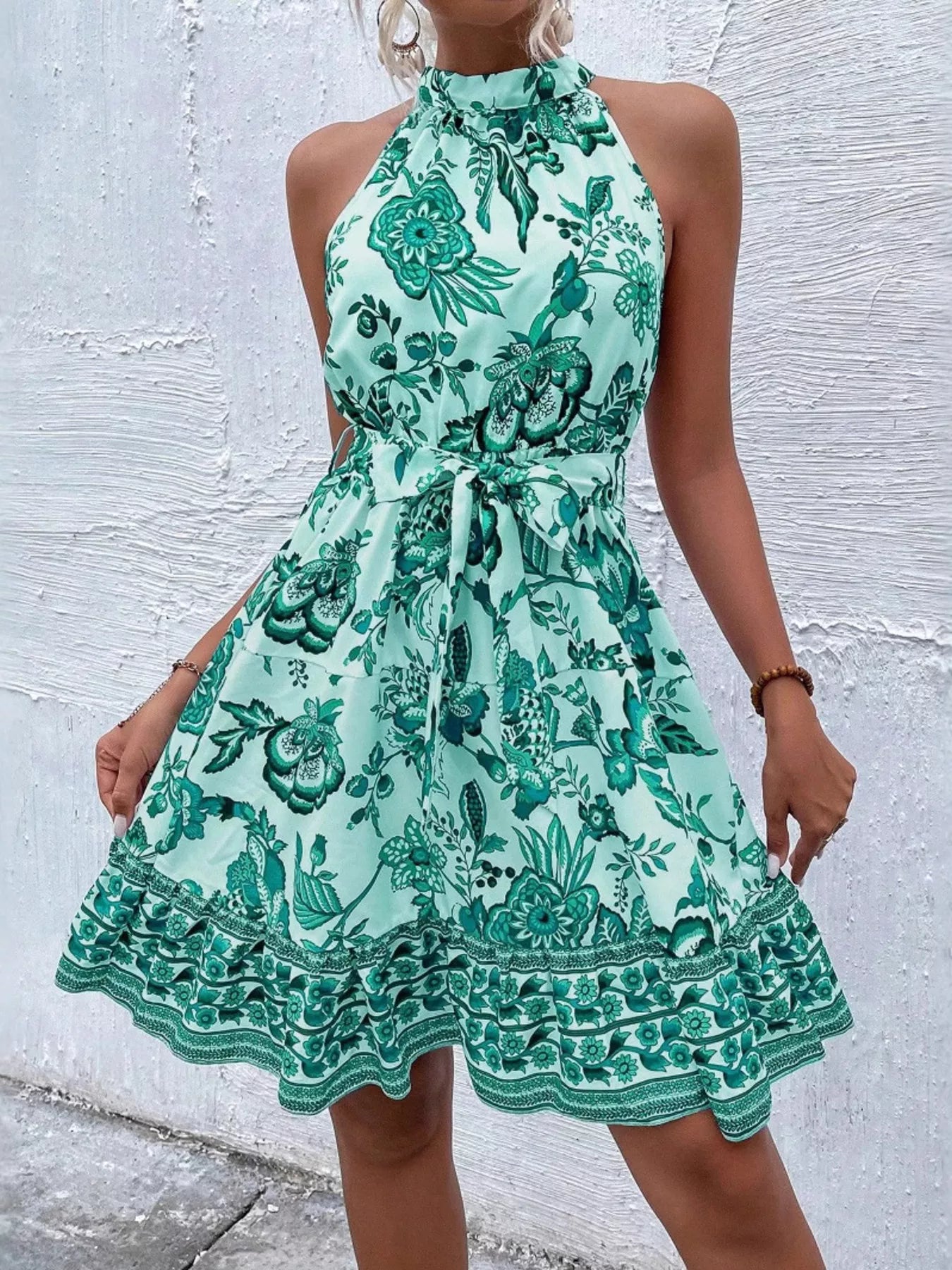 Teal printed sleeveless tie waist dress with floral pattern and tiered ruffle hem border
