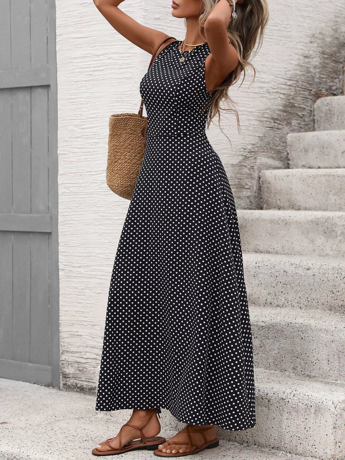 Cedar & Moore Sleeveless polka dot maxi dress in black with white dots, flowing silhouette for summer outings.