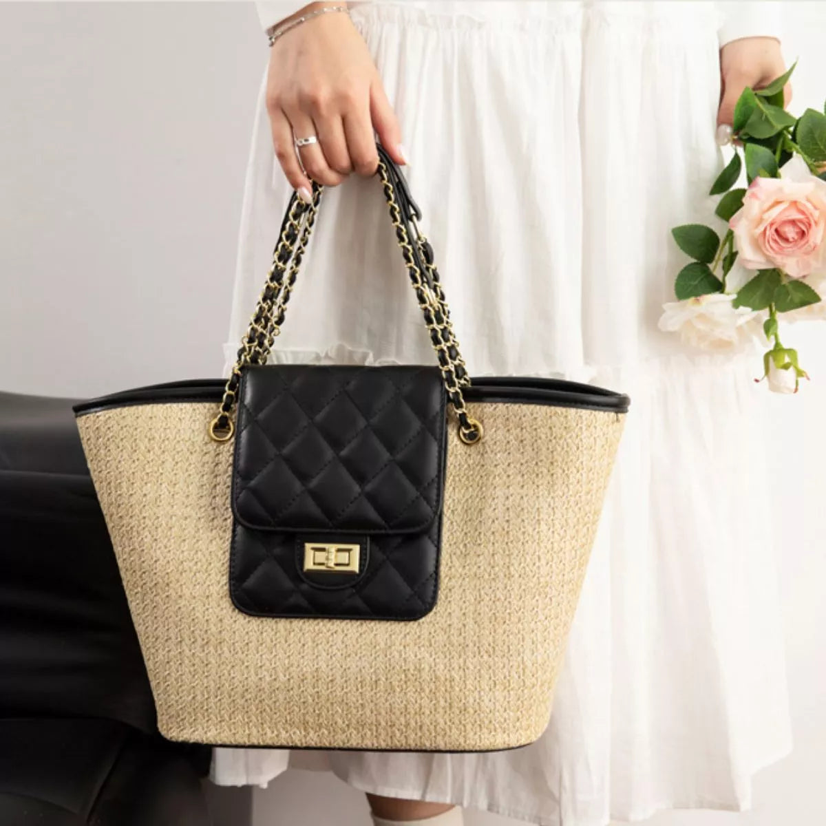 Woven straw shoulder bag with black quilted front pocket and gold-tone clasp