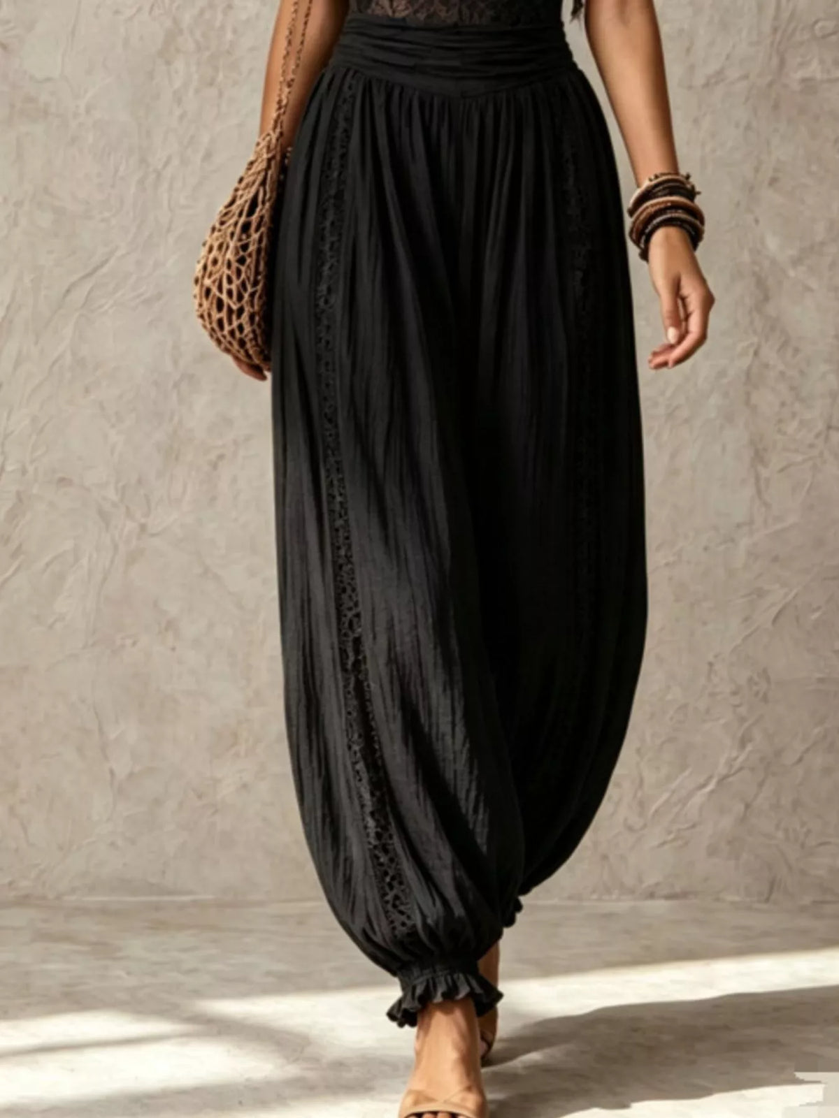 Black lace corset jumpsuit with draped harem trousers and elasticized ankle cuffs