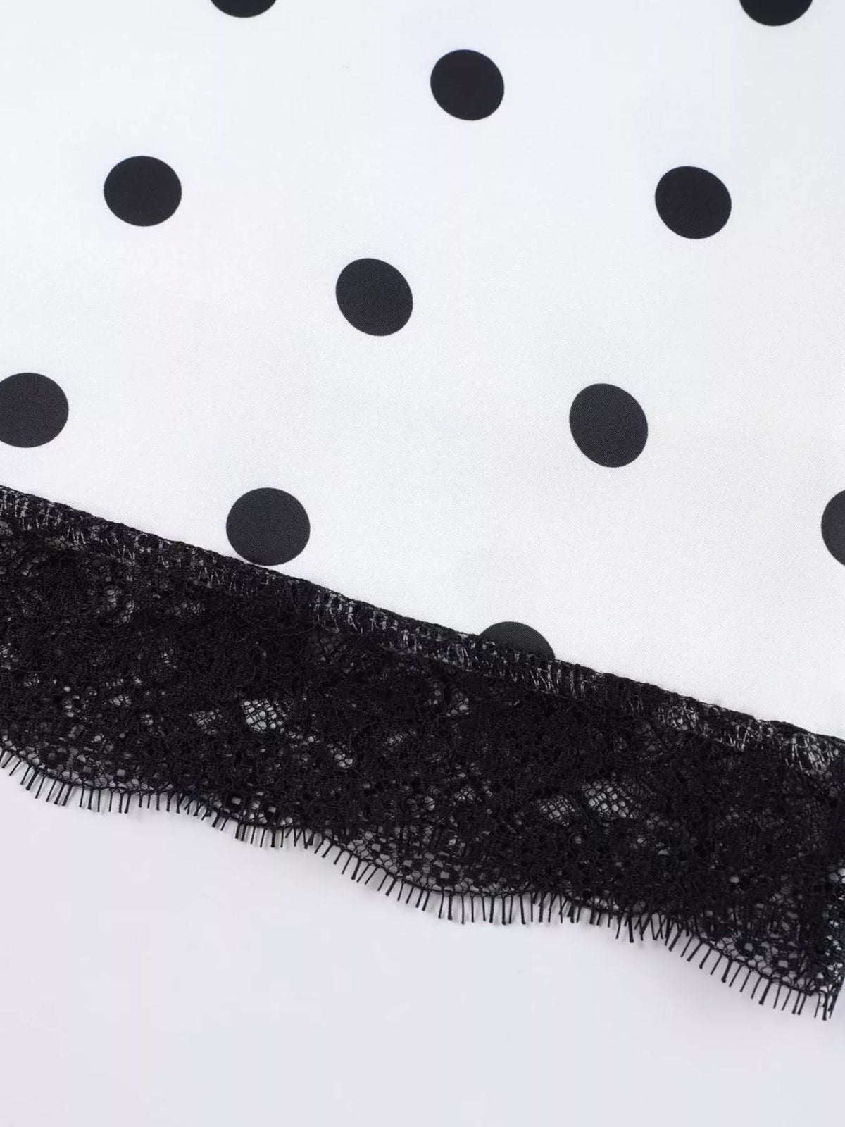 Black lace hem trim on a white skirt with black polka dots