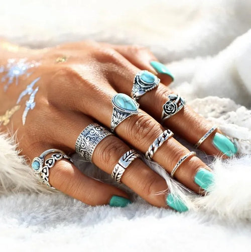 Turquoise stone and silver-tone patterned rings on hand, multiple stacked styles