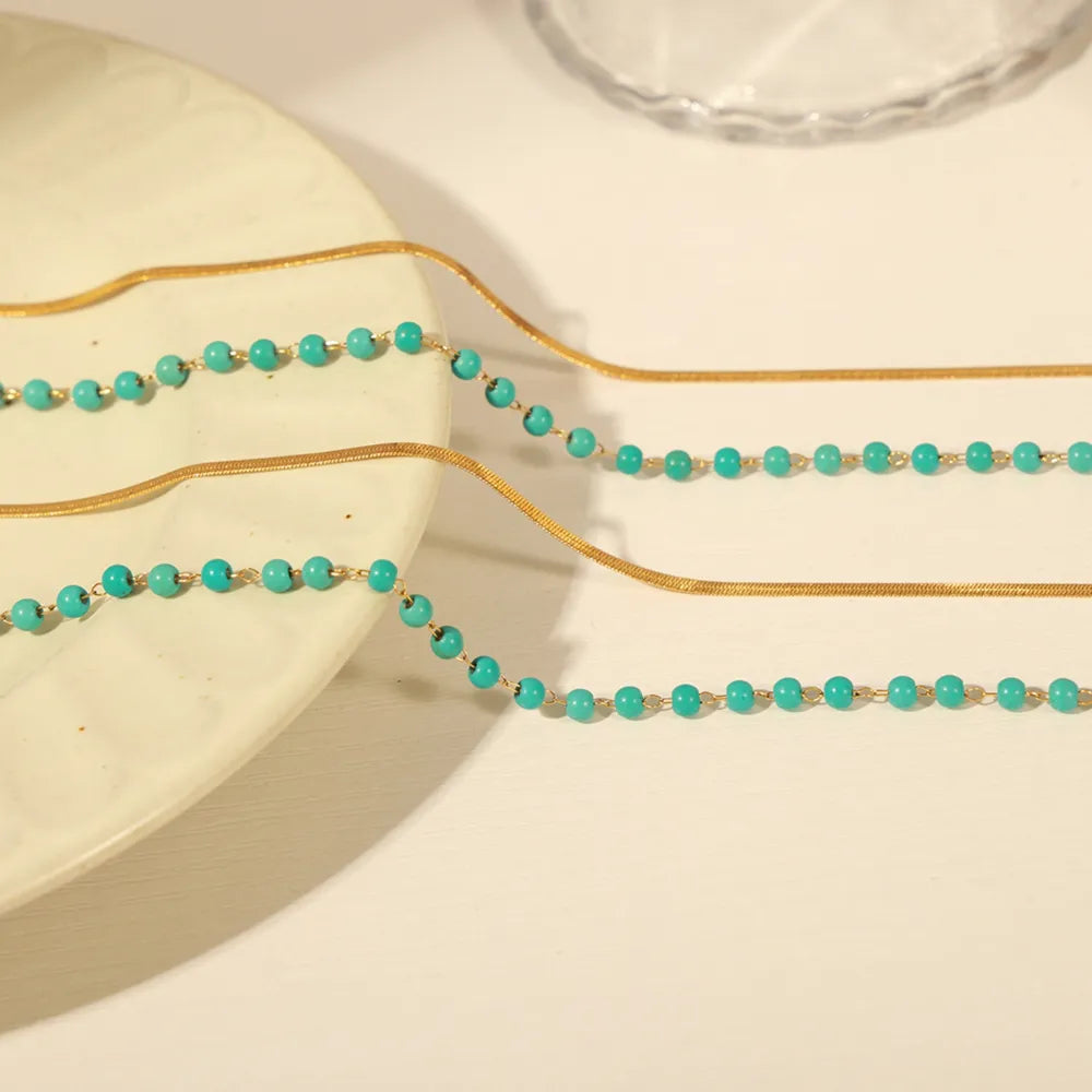 Turquoise bead double-layer necklace strands with gold chain, on light tray