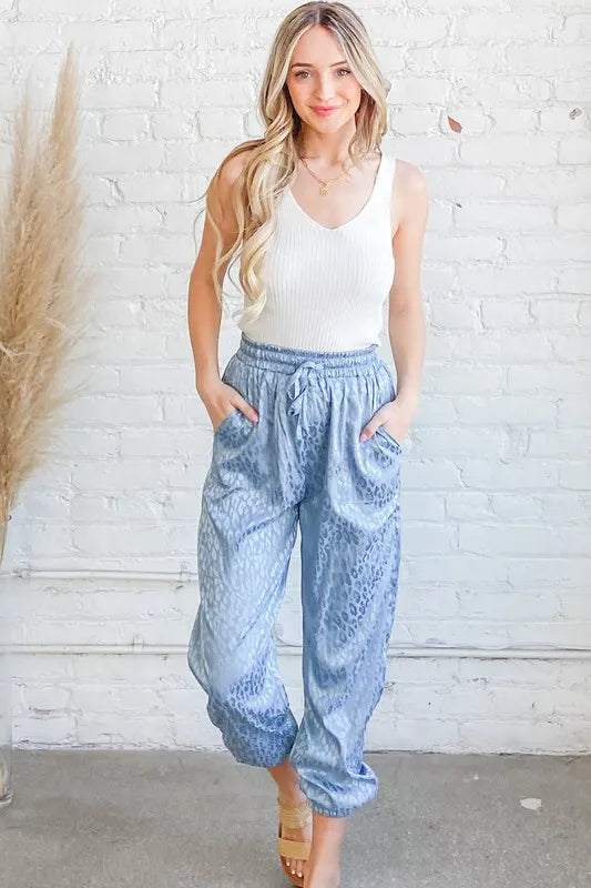 Pale blue satin leopard print joggers with gathered elastic waistband and tapered legs