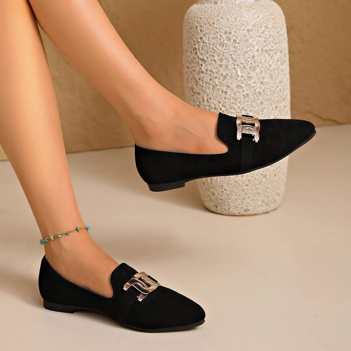 Black suede pointed loafers with chain link buckle and flat heel