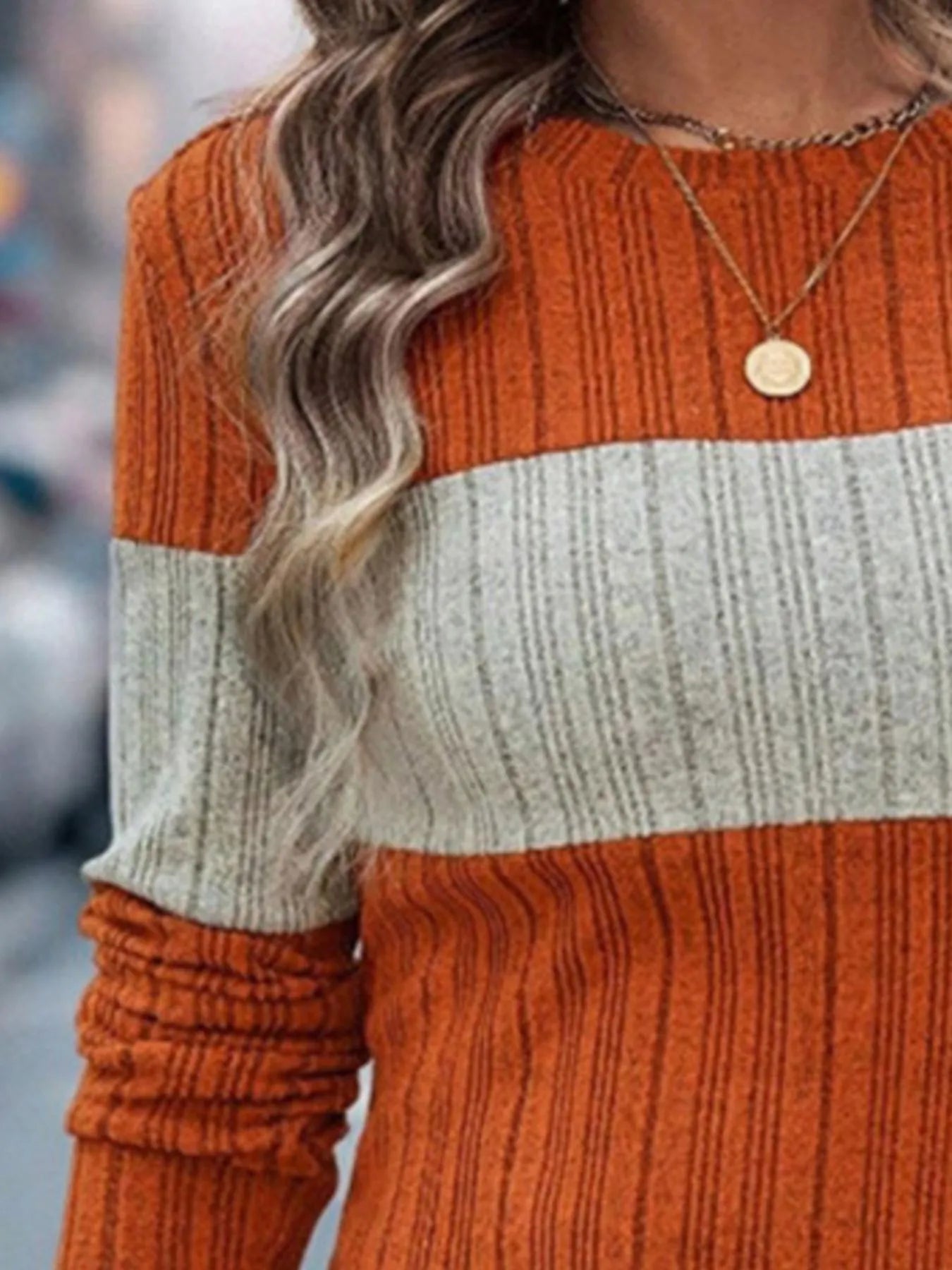 Color-block round-neck long-sleeve sweater with orange top and cream middle band.