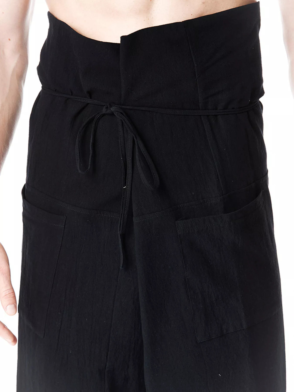 Men's loose-fit drawstring pants in dark fabric, elastic waist with tied drawcord.