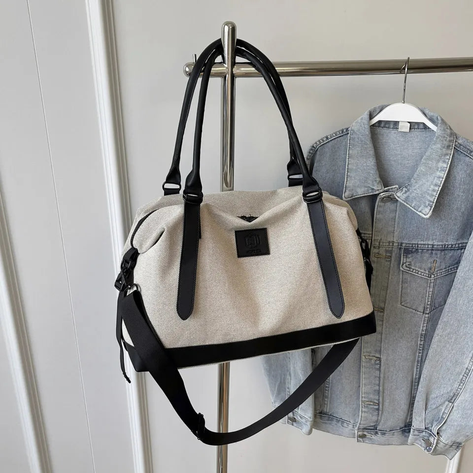 Large polyester duffle bag in cream with black contrast handles and shoulder strap