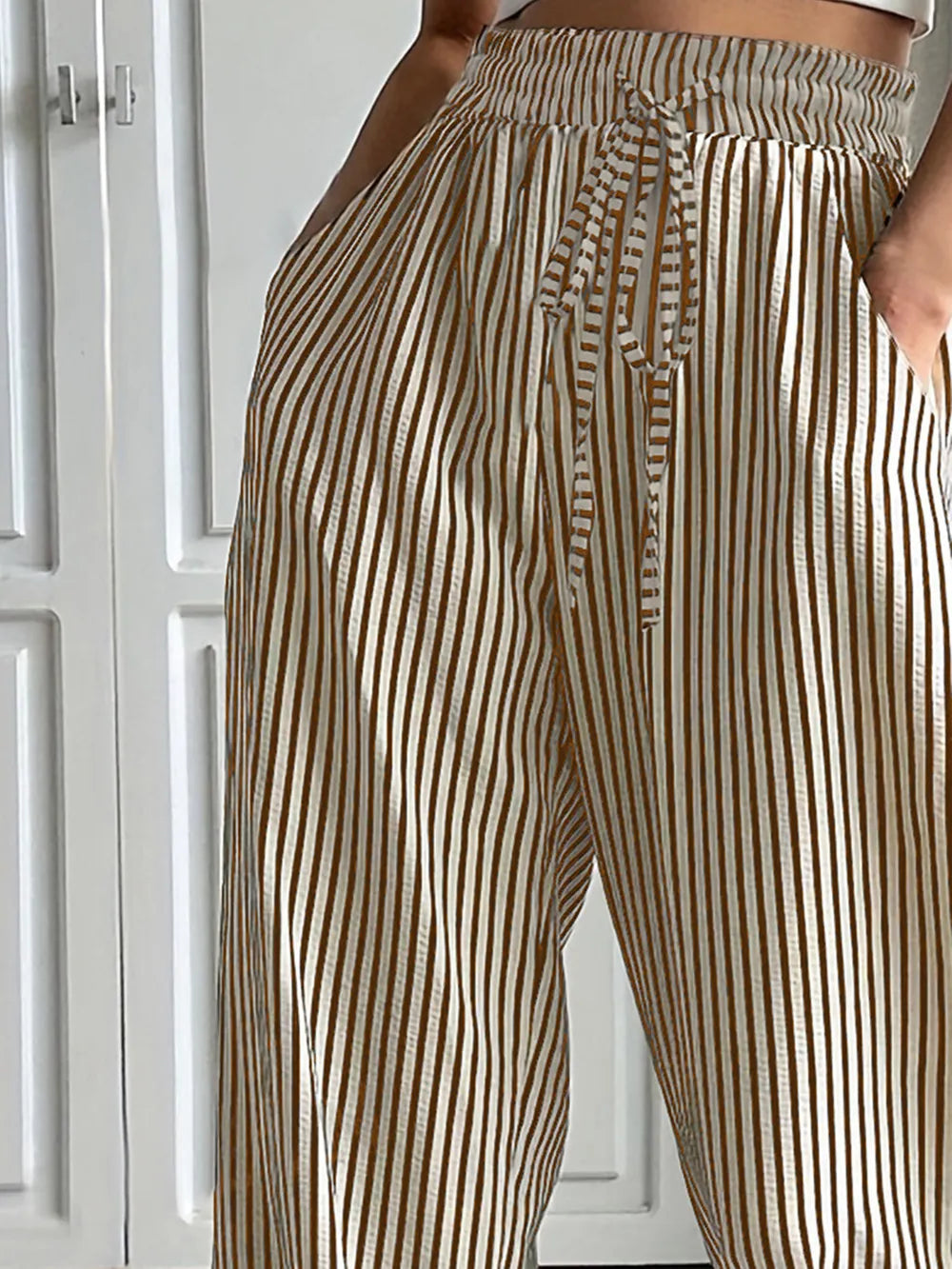 Striped elastic waist drawstring pants in tan and white, close-up of tie front