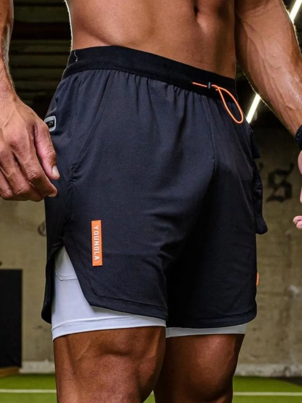 Dark drawstring shorts with black waistband and orange logo tag, white inner lining