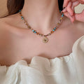 Beaded necklace with multicolor spacer beads and gold-tone sunflower-style pendant