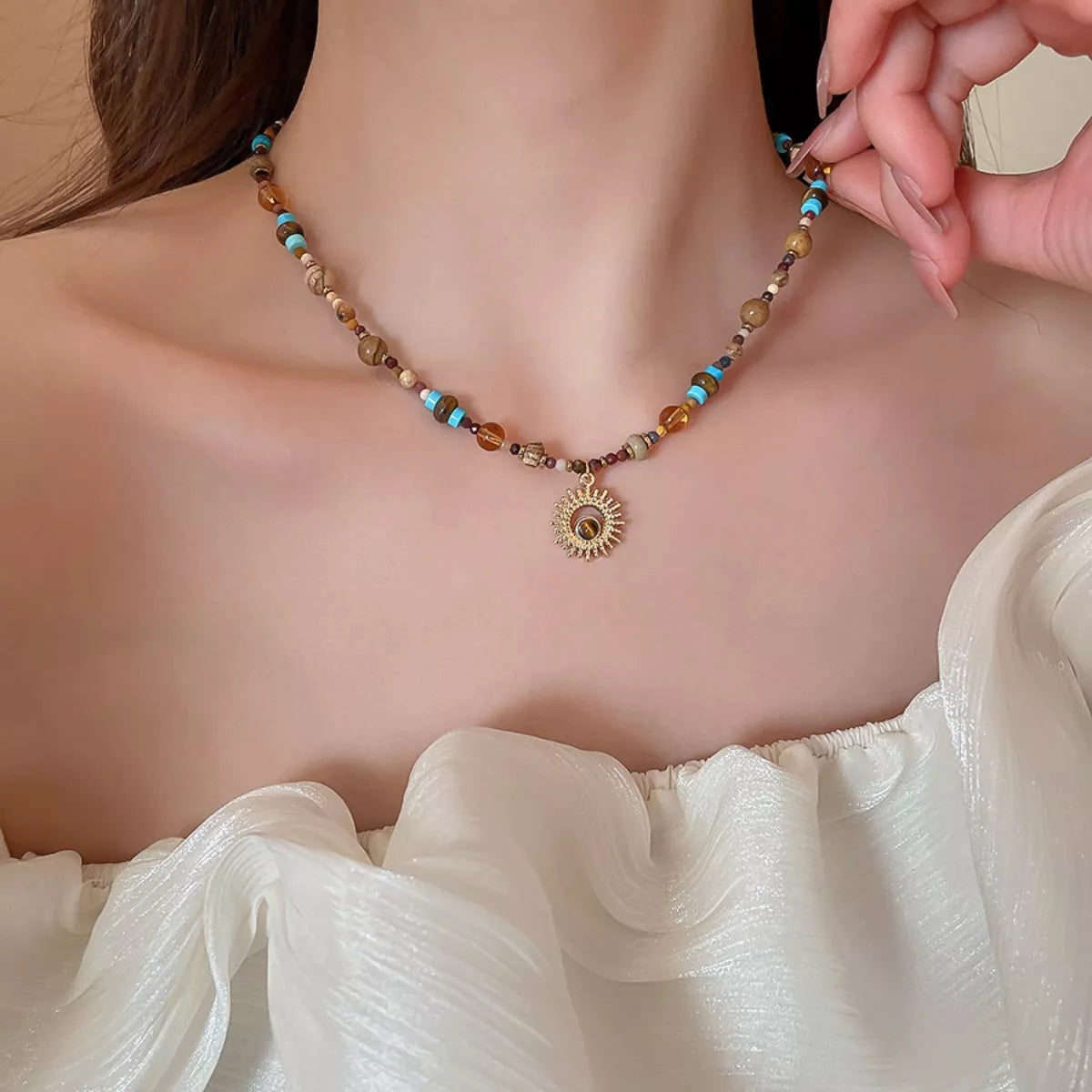 Beaded necklace with multicolor spacer beads and gold-tone sunflower-style pendant
