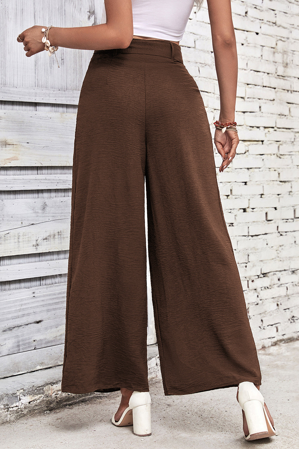 High-waisted wide-leg pants in dark brown with centered crease and belt.