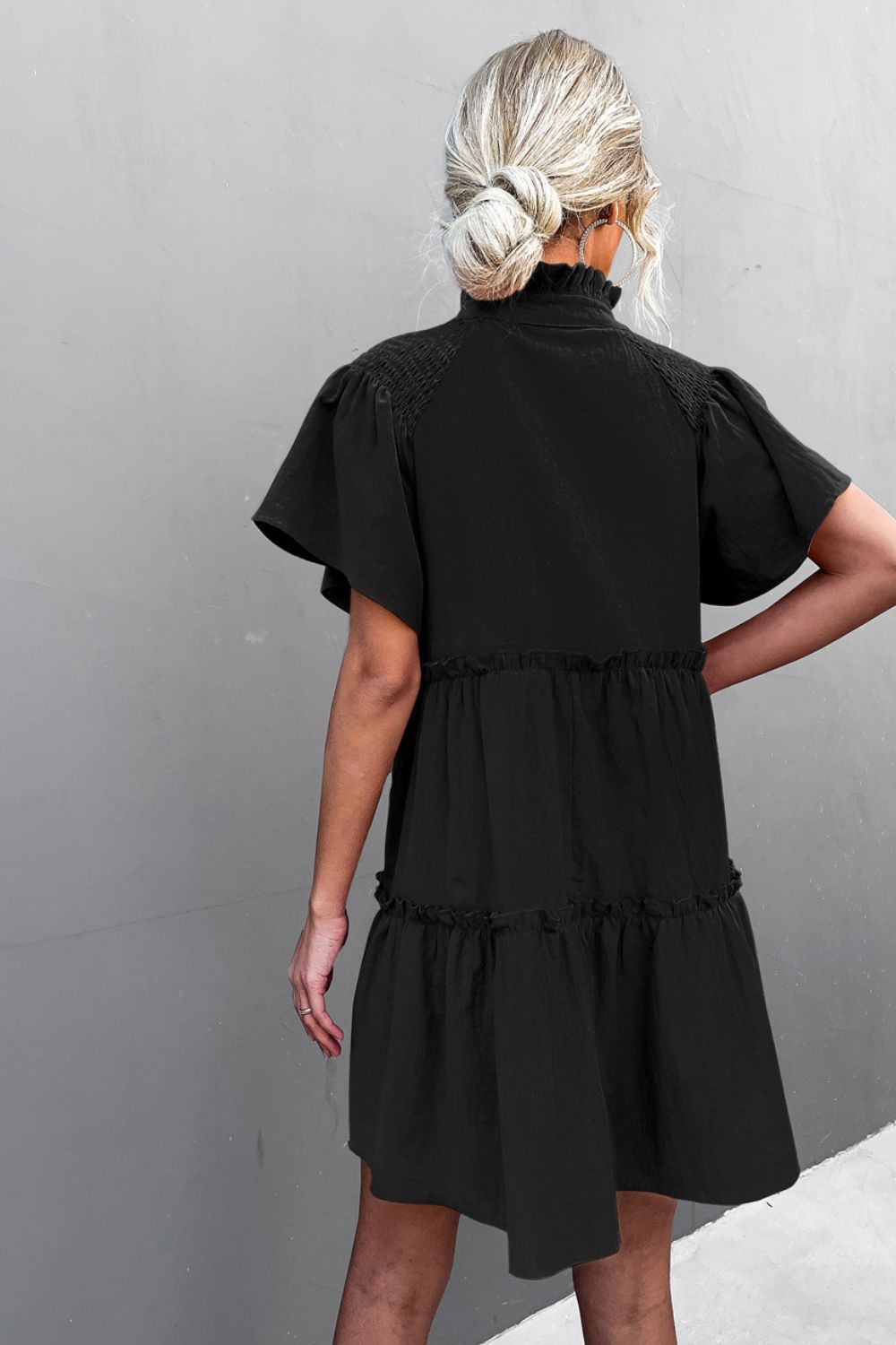 Black smocked tie-neck tiered frill dress with short puff sleeves, back view