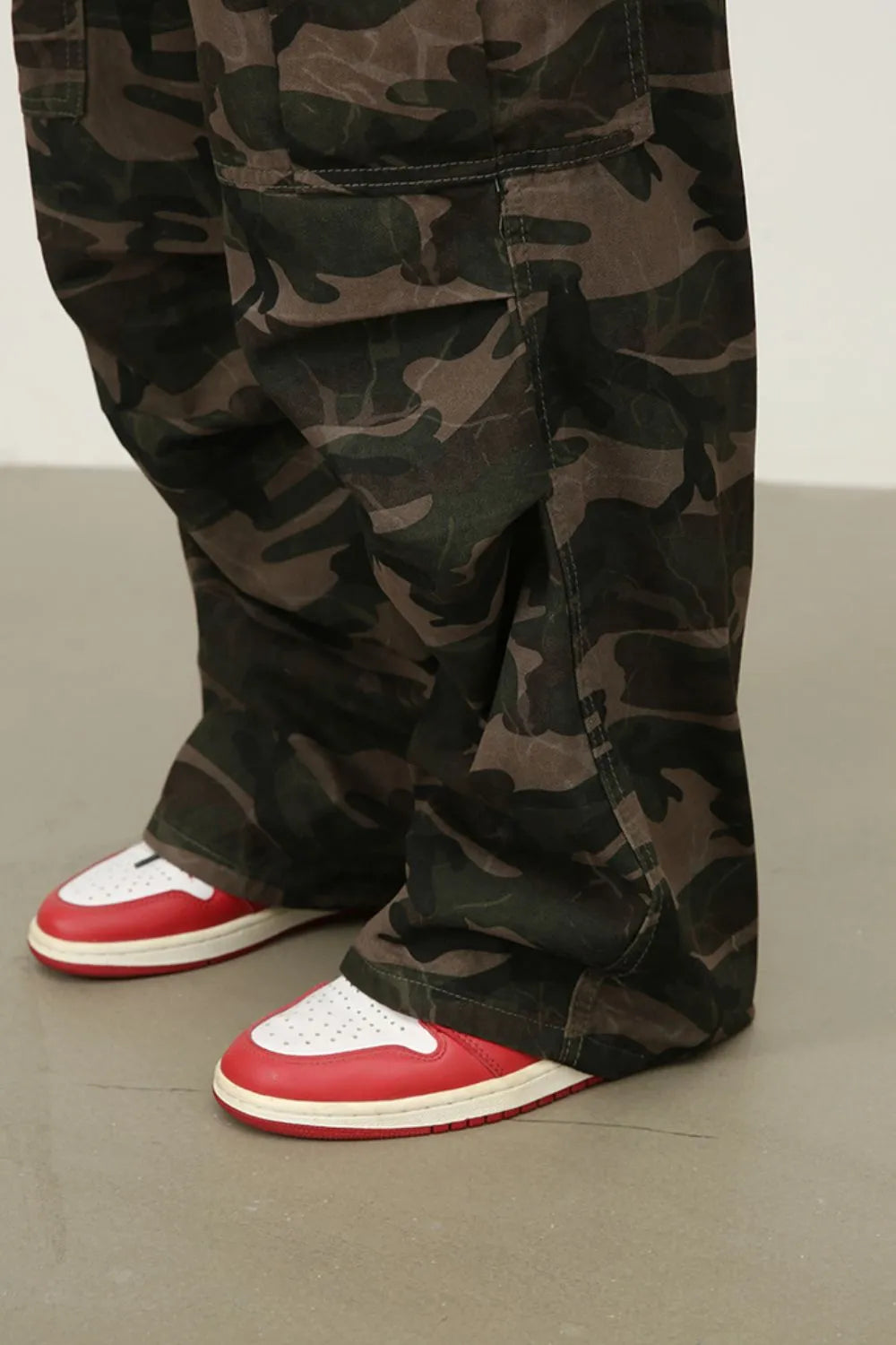 Green camouflage cargo jeans on model, showing leg and pocket seams near hem