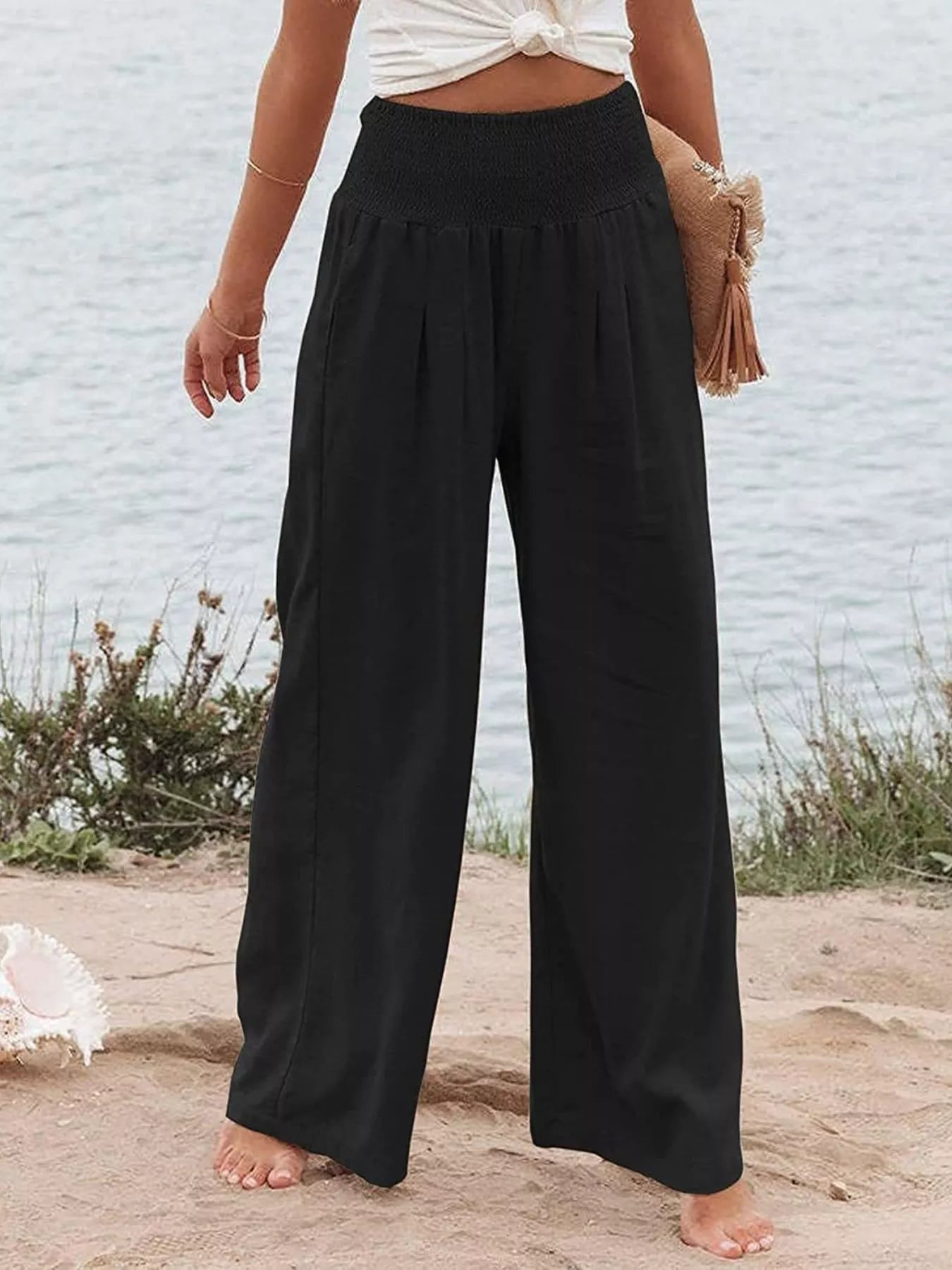 Black smocked high-waist wide-leg pants with elastic waistband and loose legs.