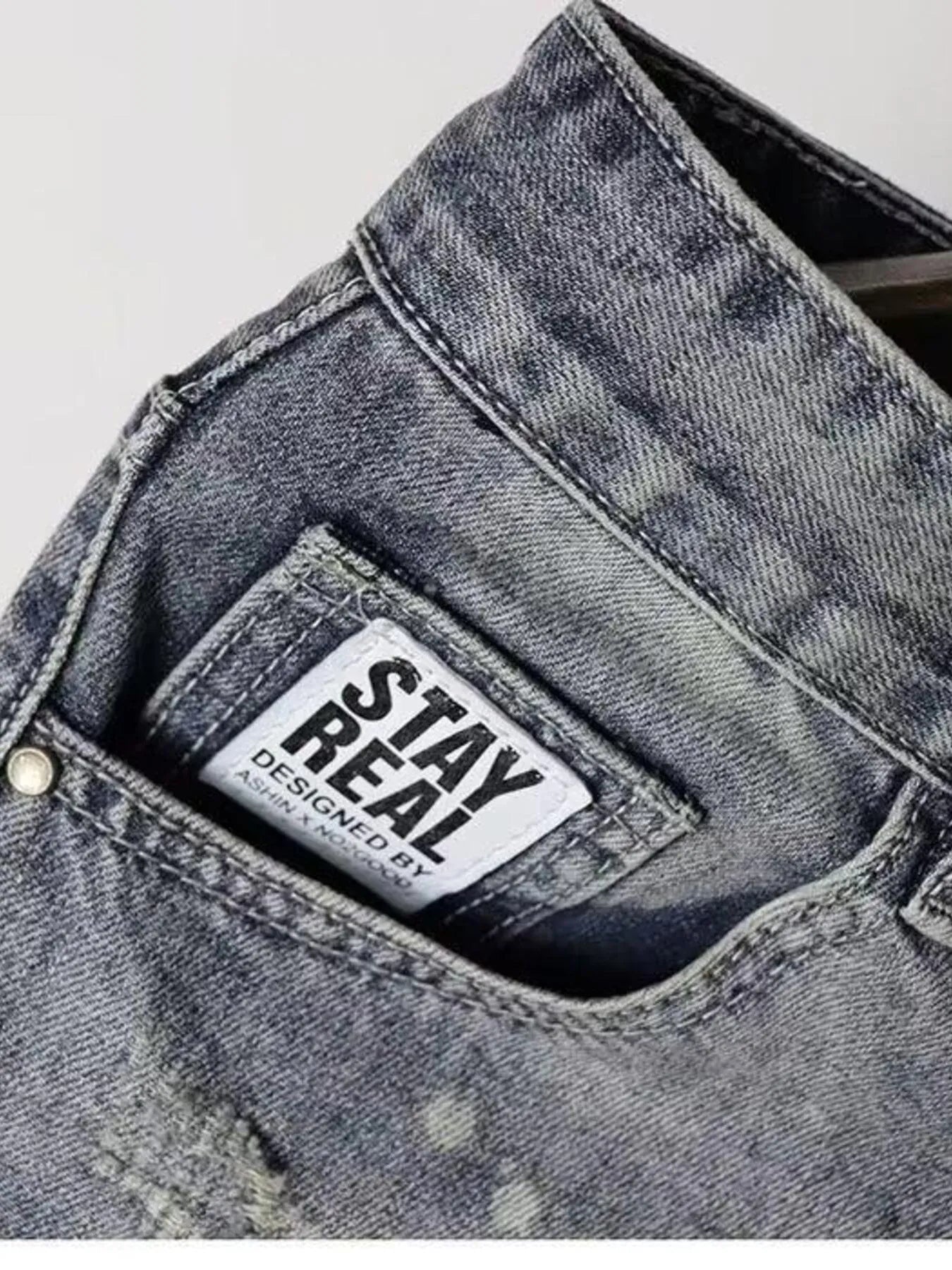 Light gray denim shorts with 'STAY REAL' label patch on the waistband