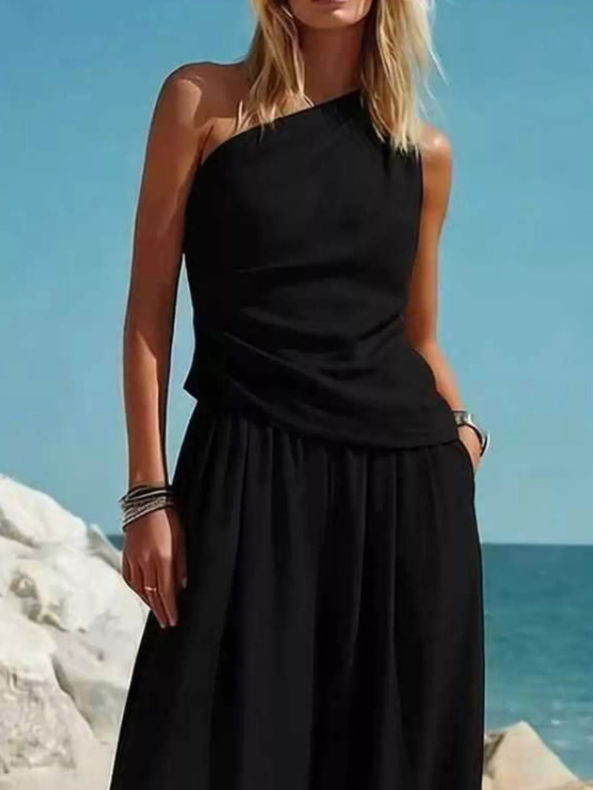 Black one-shoulder sleeveless draped top with gathered waist, paired with harem pants
