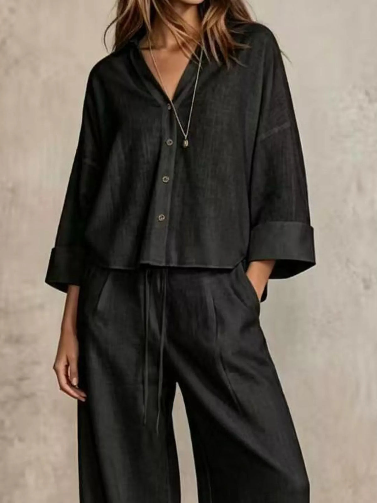 Black button-down shirt and wide-leg pants set, short sleeves, top buttons visible.