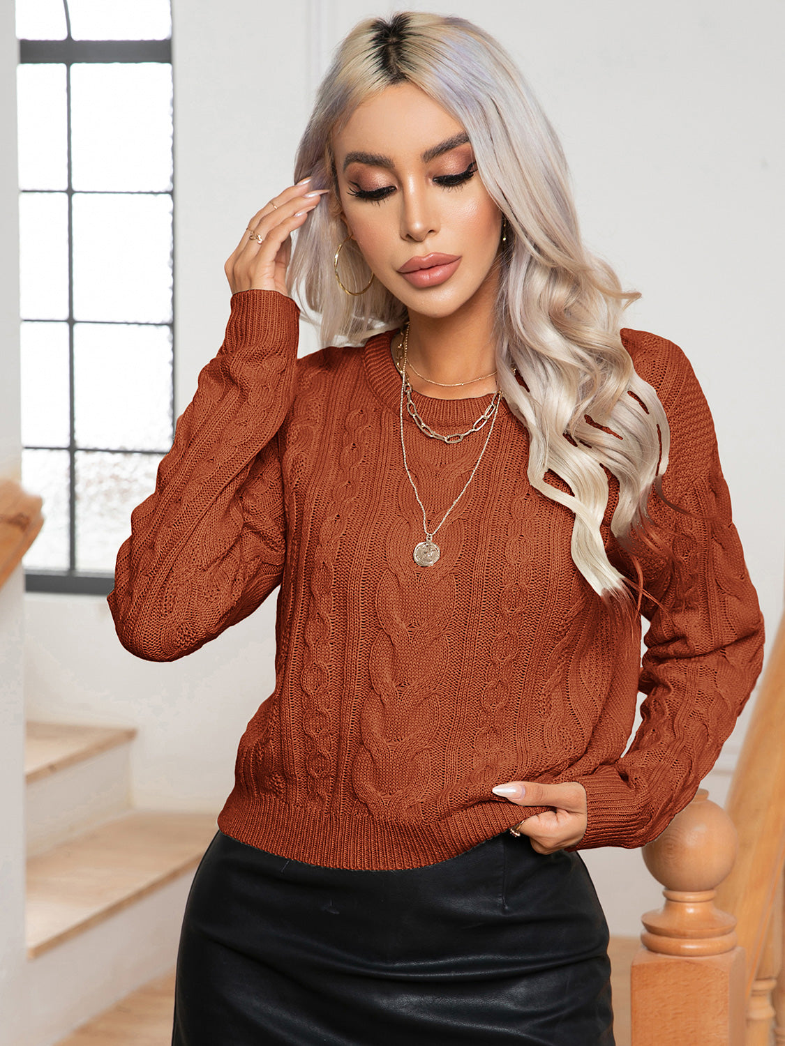 Caramel cable-knit round-neck sweater with long sleeves, cable texture, and ribbed cuffs