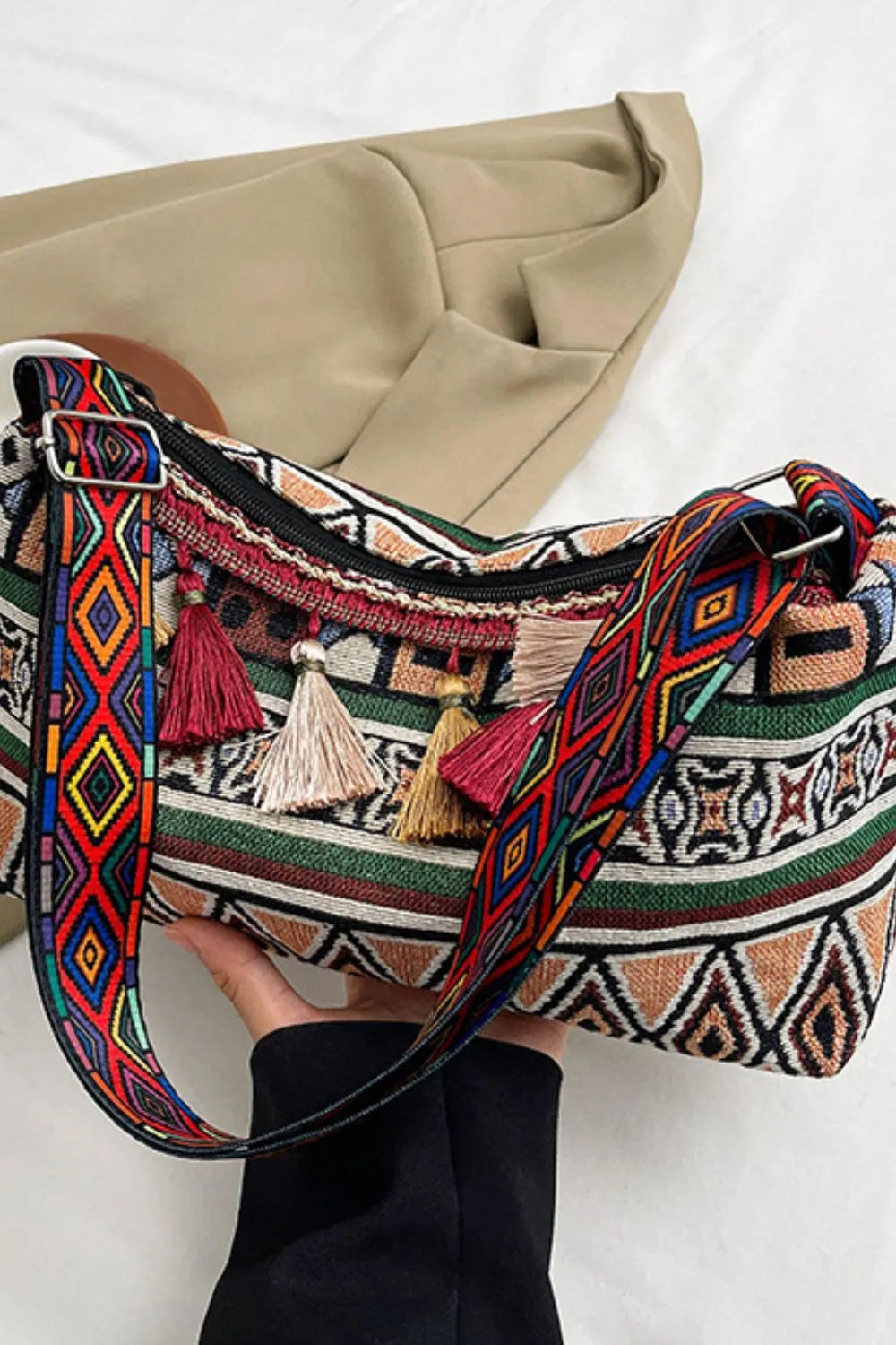 Tassel shoulder bag with adjustable strap, multicolor patterned front with hanging tassels.