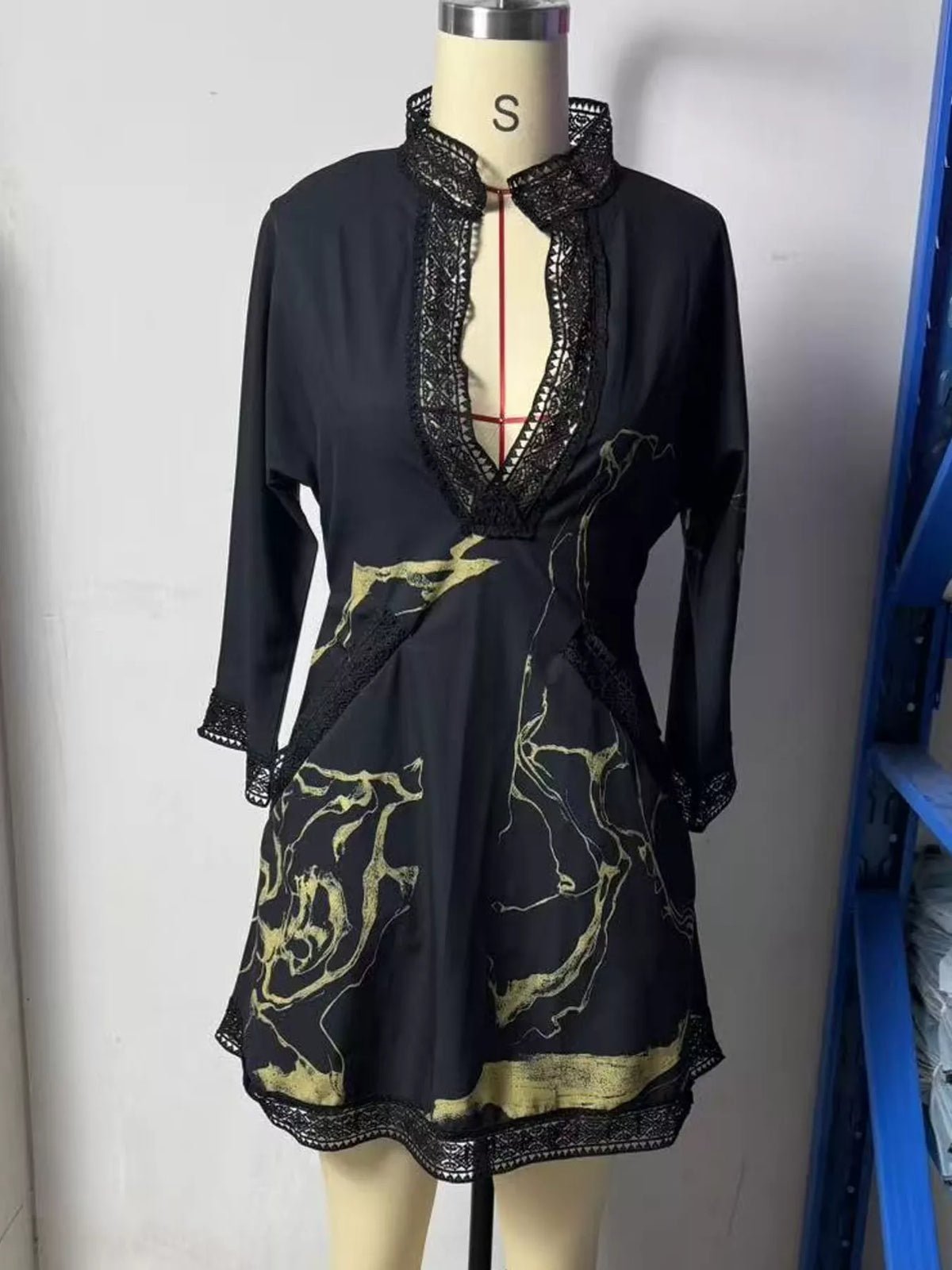 Black mini dress on mannequin with V-neck lace trim and gold patterned front
