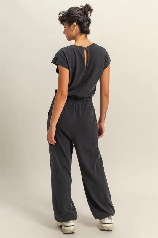 Black jumpsuit with open V-back detail, elastic drawstring waist, wide-leg pants.