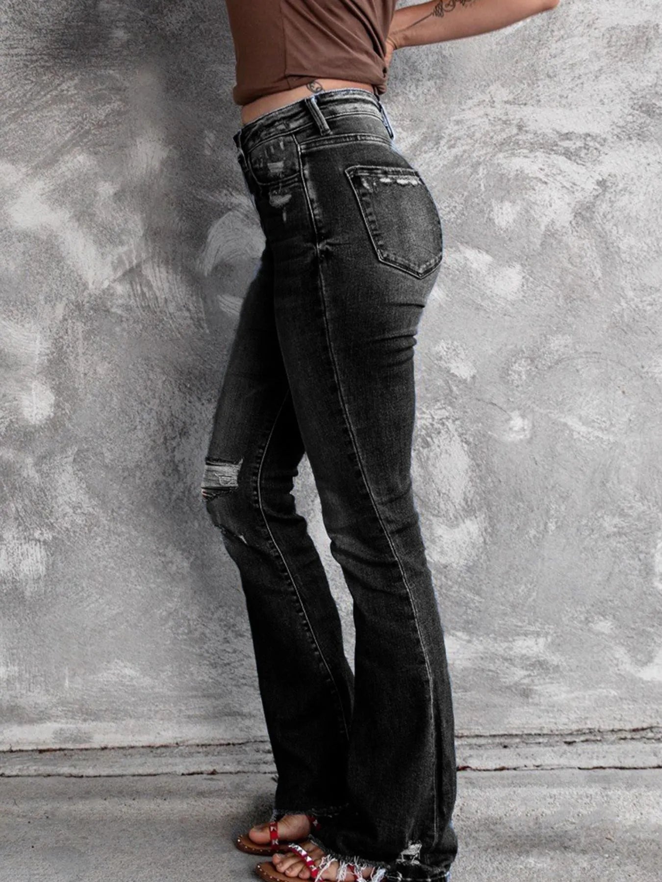 Black distressed flare jeans with back pocket distress and frayed flared hems