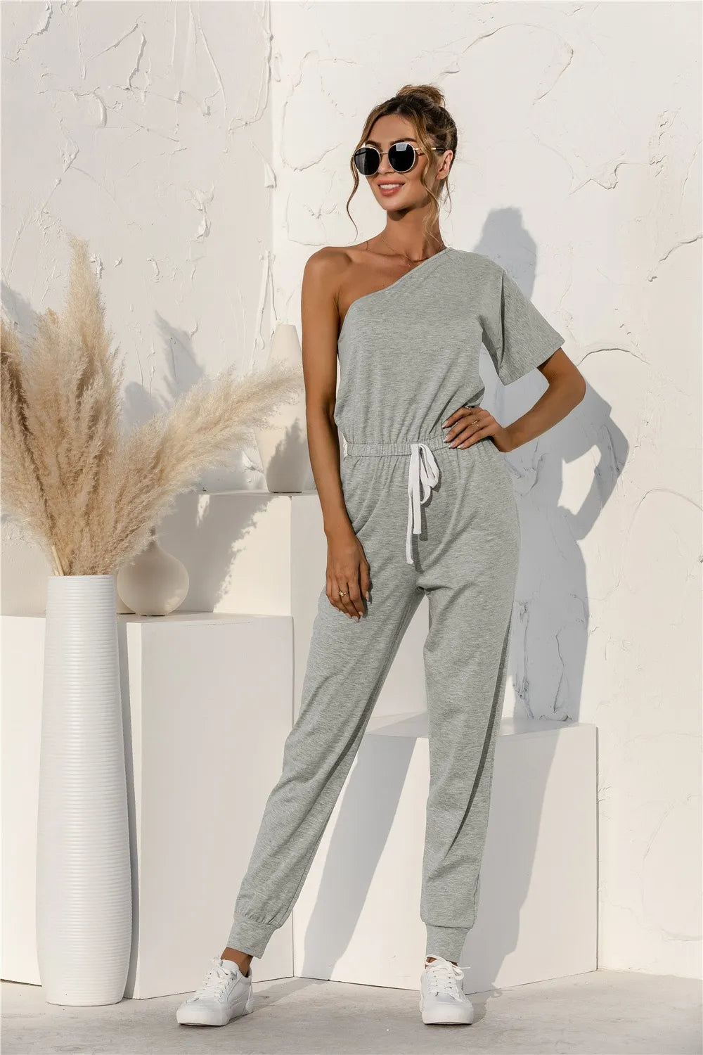 Gray single-shoulder short-sleeve jumpsuit with elastic drawstring waist and tapered legs