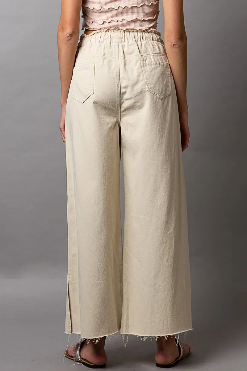 Cream distressed wide-leg drawstring pants with relaxed straight legs and frayed hem