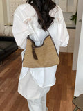 Camel woven shoulder bag with dark leather trim and small hanging tag