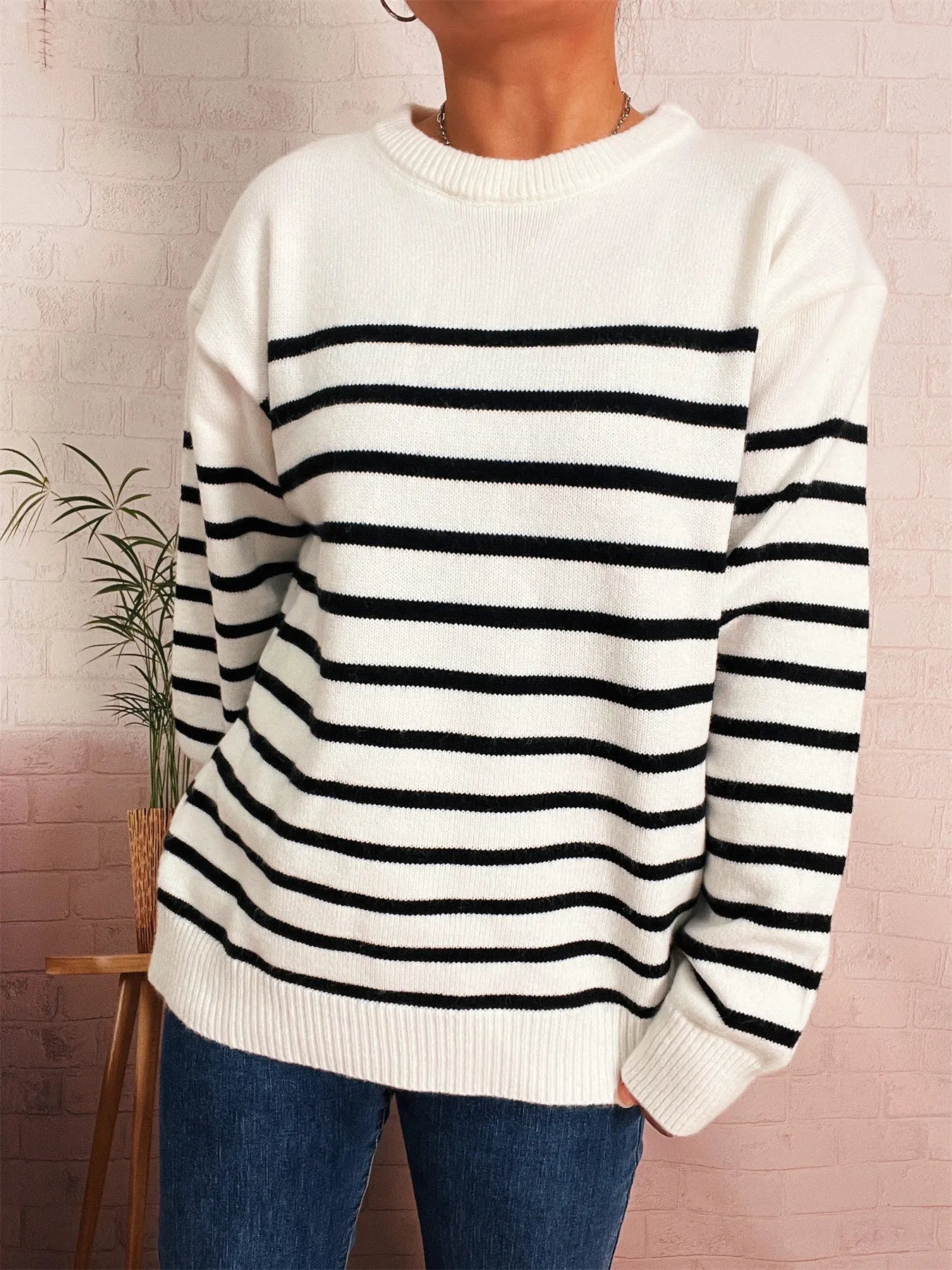 White striped round-neck sweater with black bands across chest, long sleeves