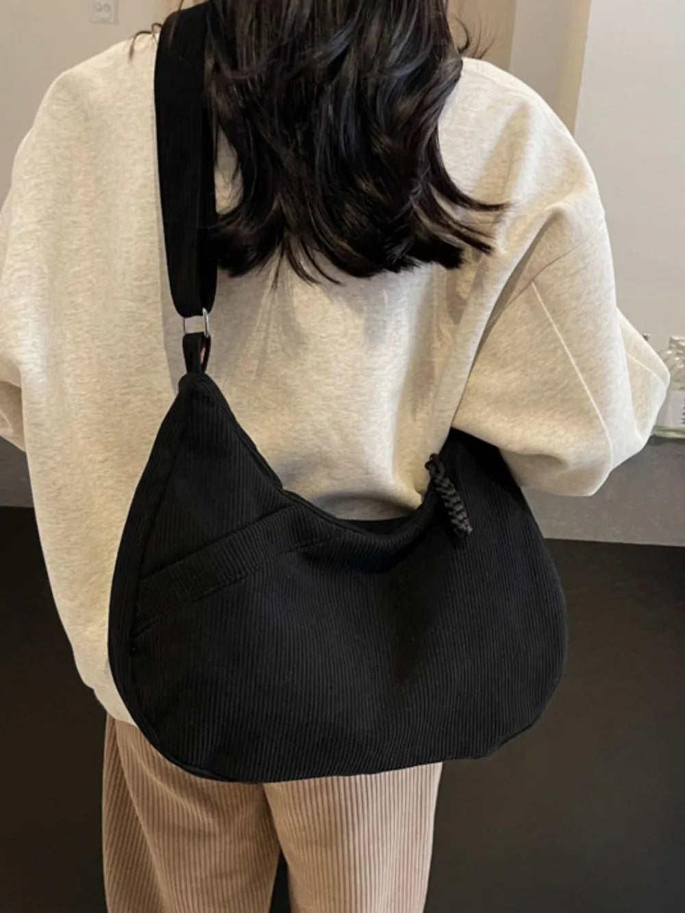 Black ribbed shoulder bag with adjustable strap and drawstring top