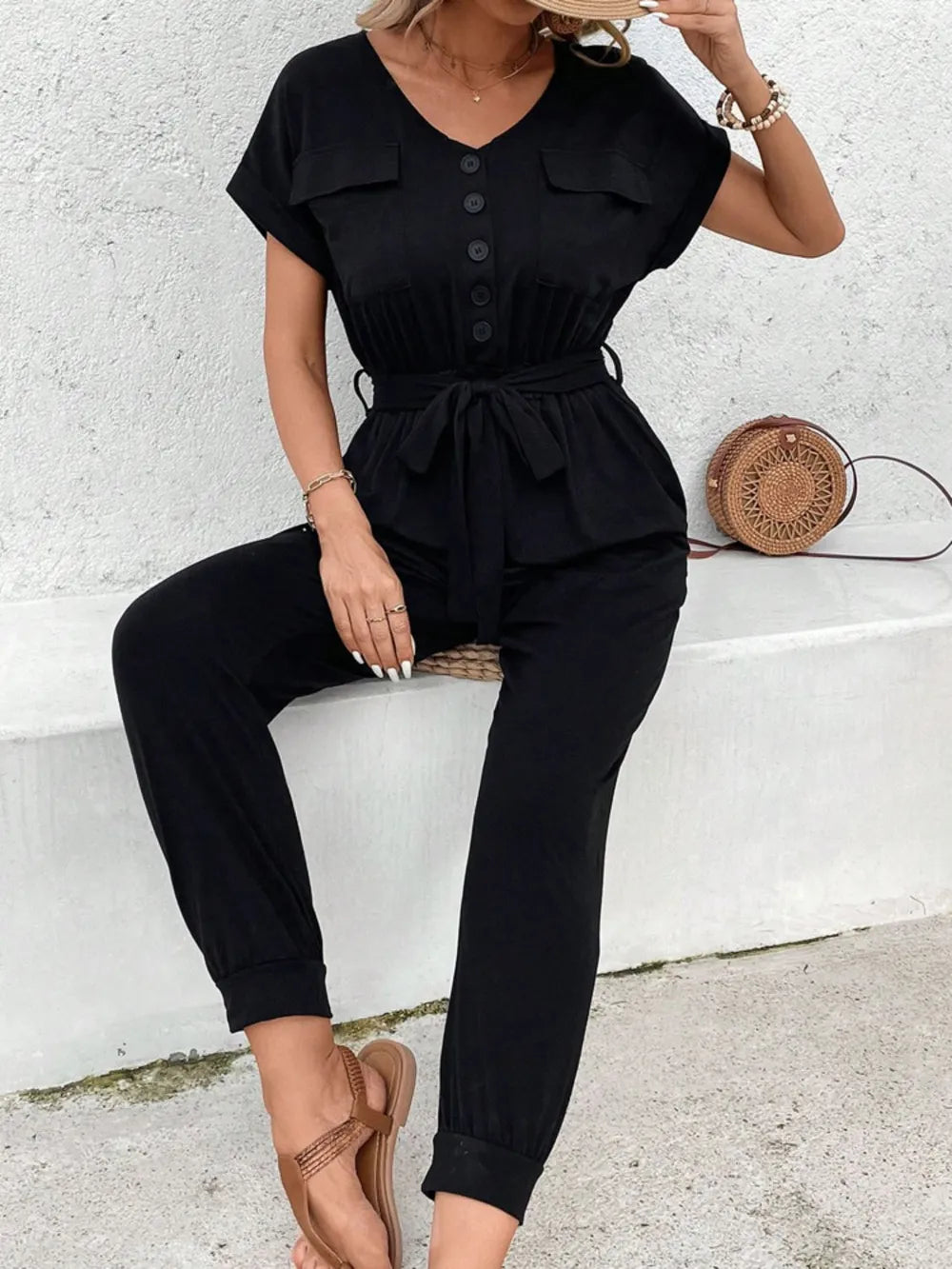 Black V-neck short-sleeve jumpsuit with chest buttons, drawstring waist, cuffed legs