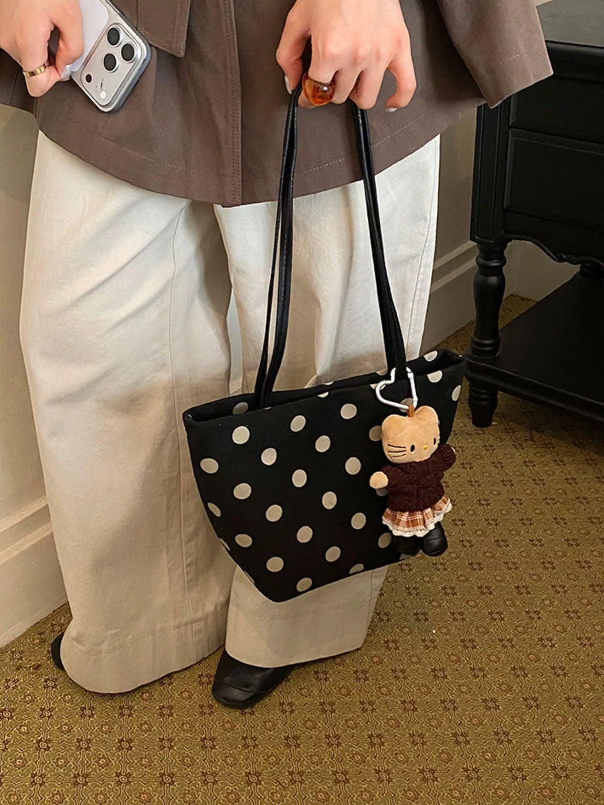 Black suede shoulder handbag with white polka dots and cat charm keychain