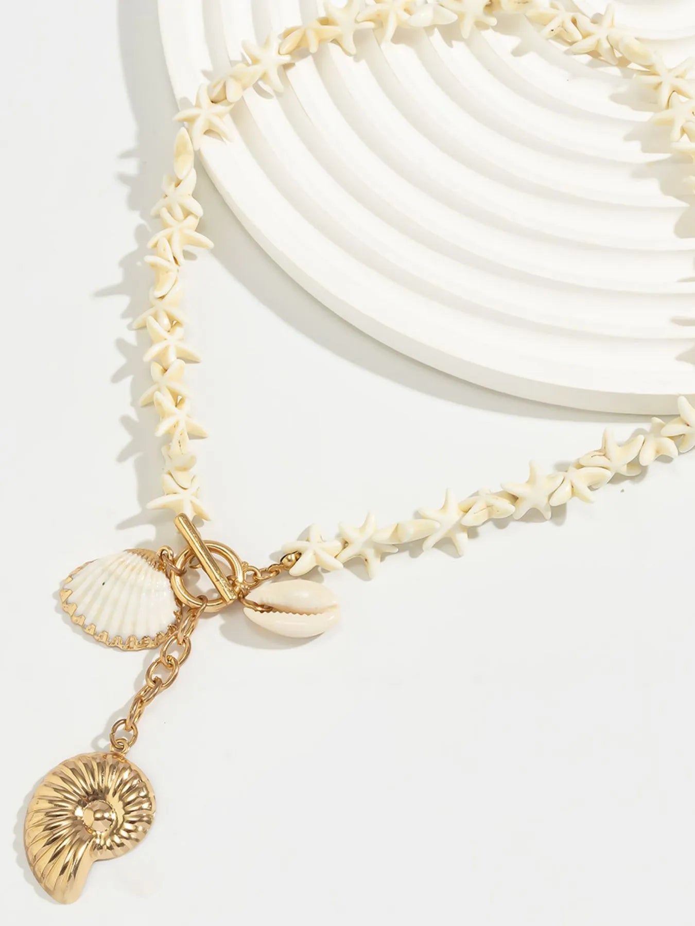 Gold shell pendant necklace detail with starfish-shaped links, clasp, and shell charms